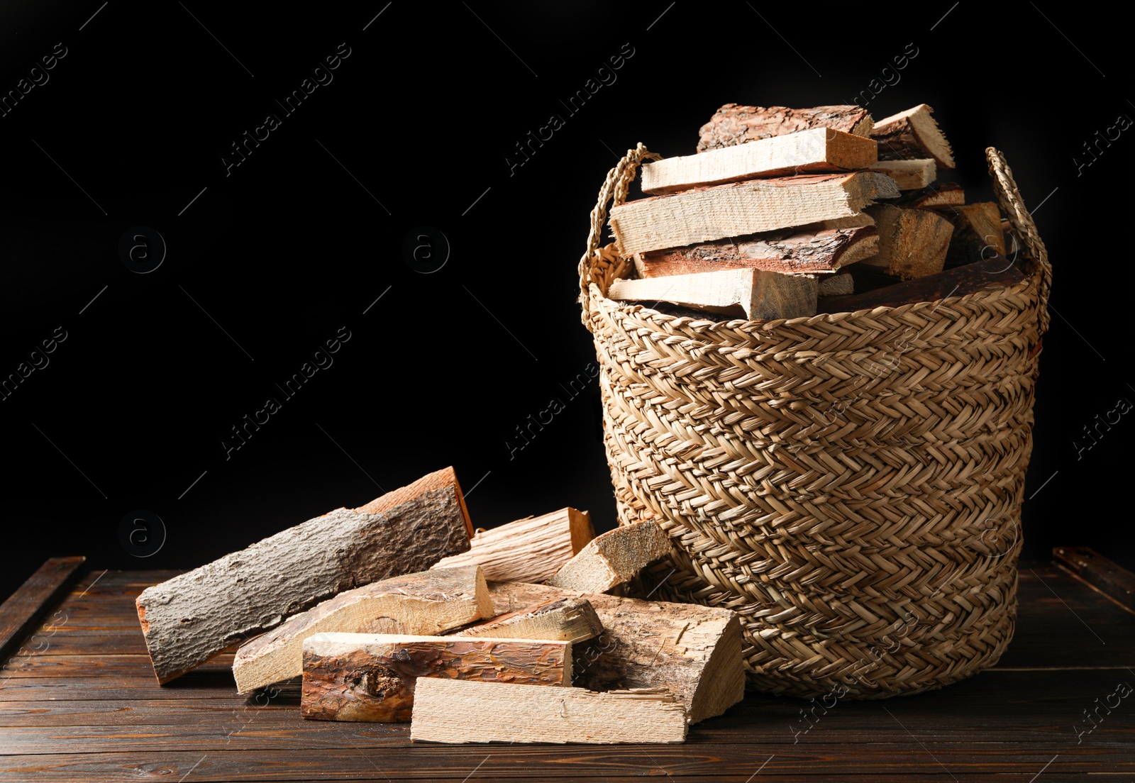 Photo of Cut firewood on table against black background