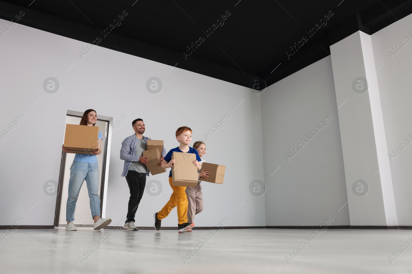 Photo of Happy family with moving boxes entering in new apartment. Settling into home