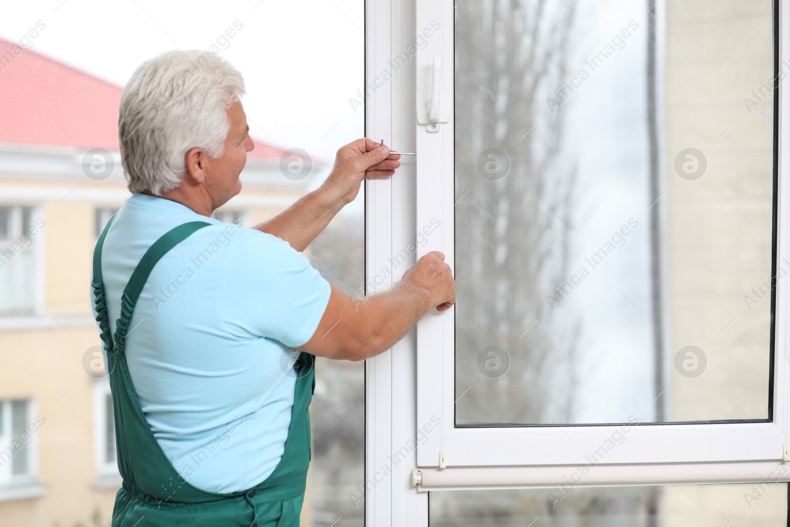 Photo of Mature construction worker repairing plastic window indoors