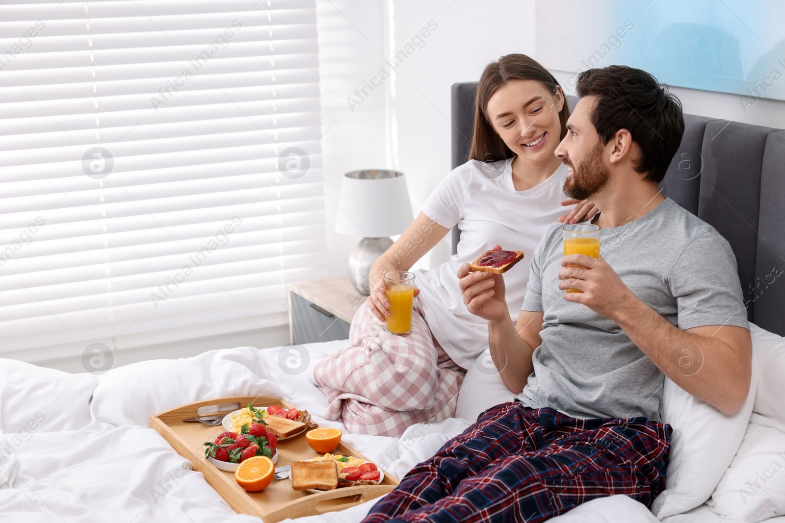 Photo of Happy couple having breakfast in bedroom. Space for text