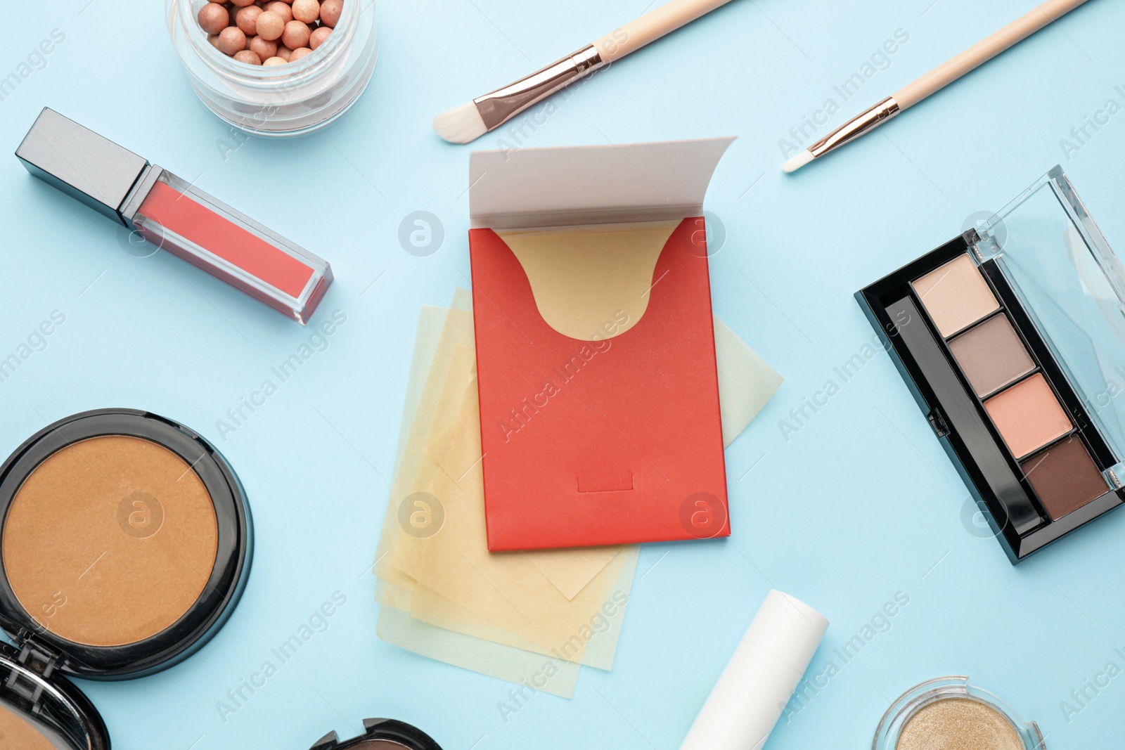 Photo of Flat lay composition with facial oil blotting tissues and makeup products on light blue background. Mattifying wipes