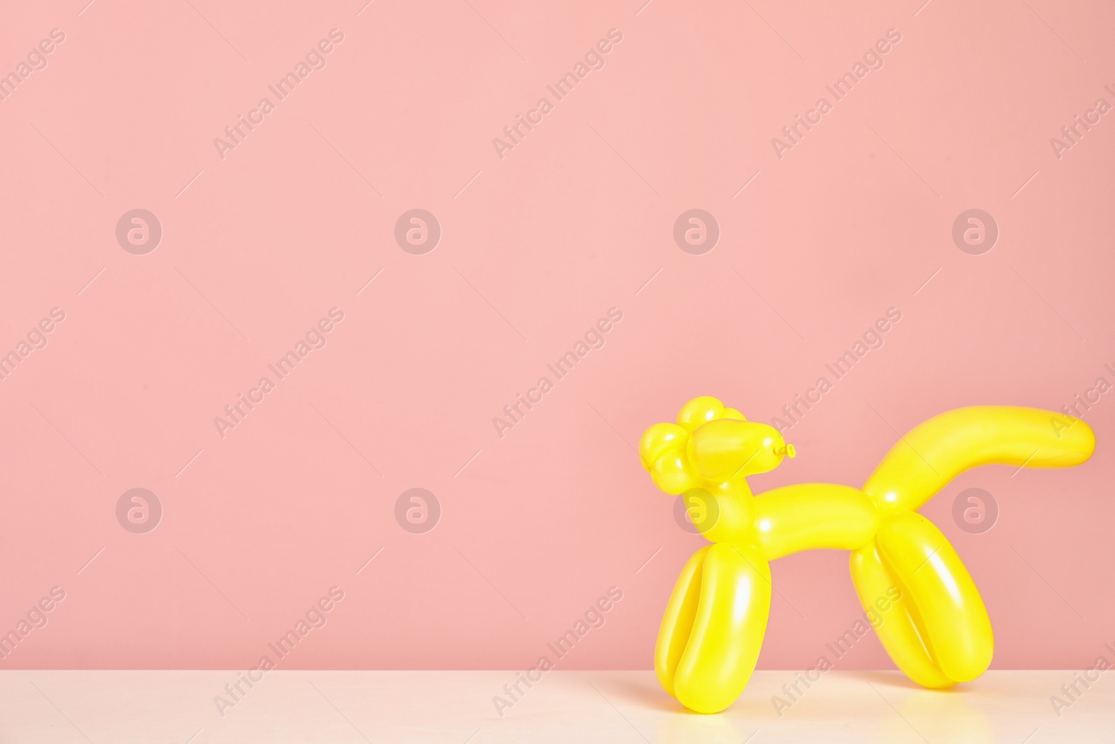 Photo of Animal figure made of modelling balloon on table against color background. Space for text