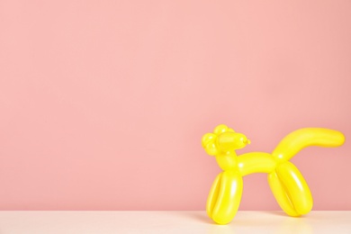 Photo of Animal figure made of modelling balloon on table against color background. Space for text