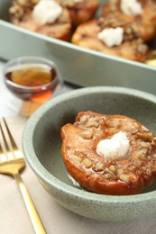 Photo of Tasty baked quince with nuts and cream cheese in bowl on table, closeup