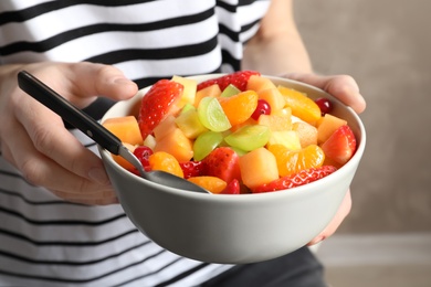 Photo of Woman with bowl of fresh fruit salad, closeup