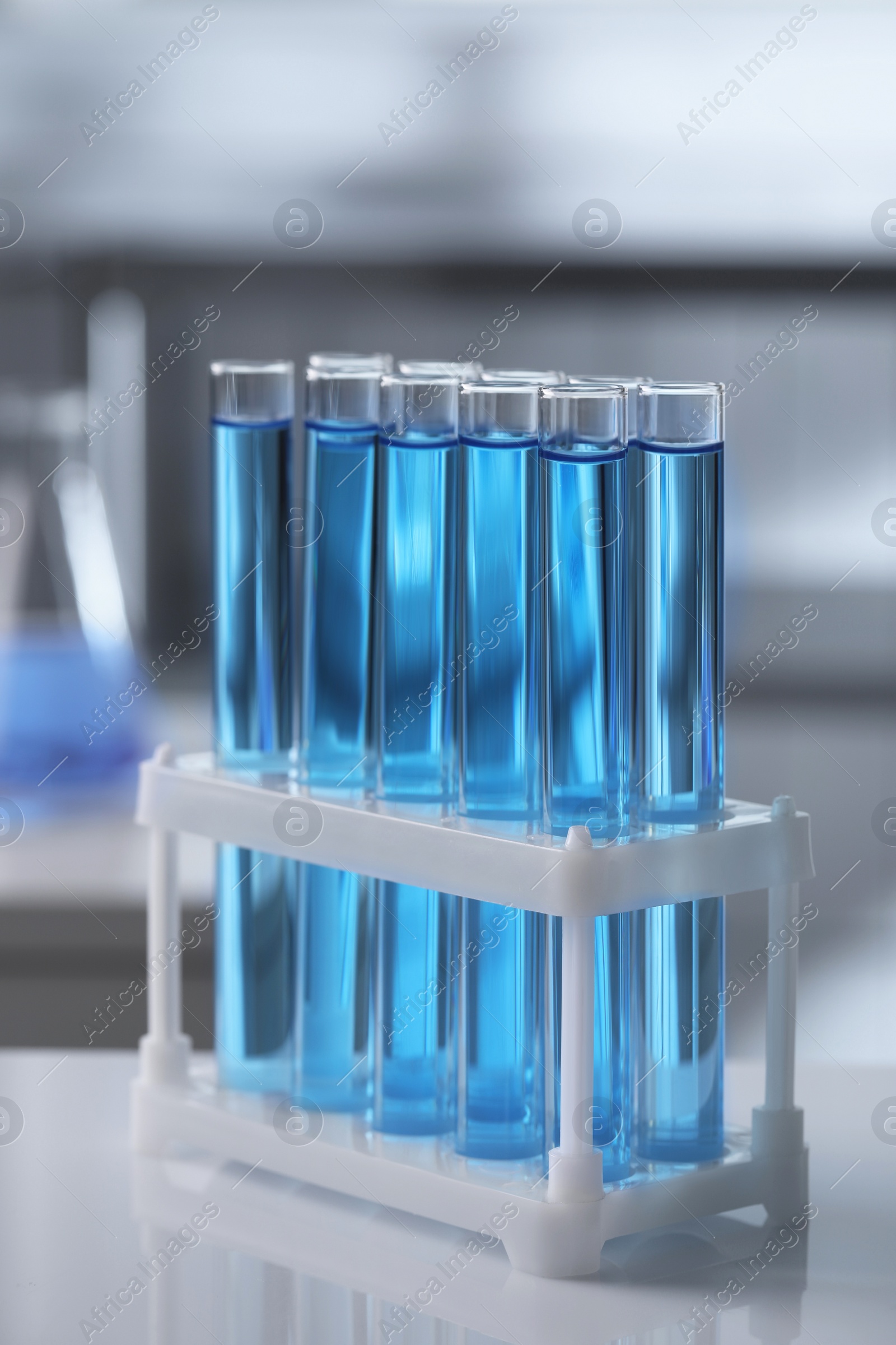 Photo of Test tubes with light blue liquid on table in laboratory