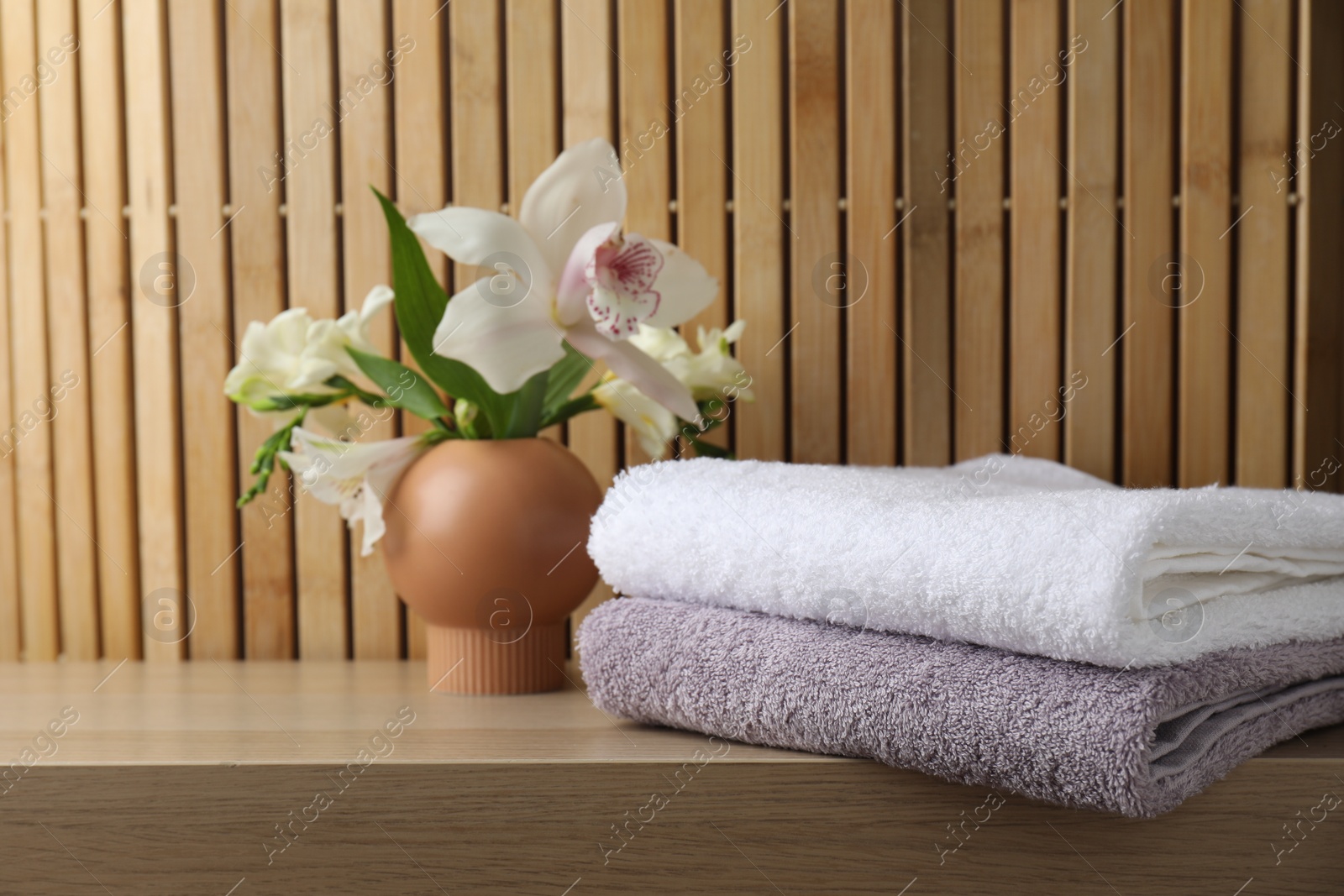 Photo of Terry towels and beautiful flowers on wooden table