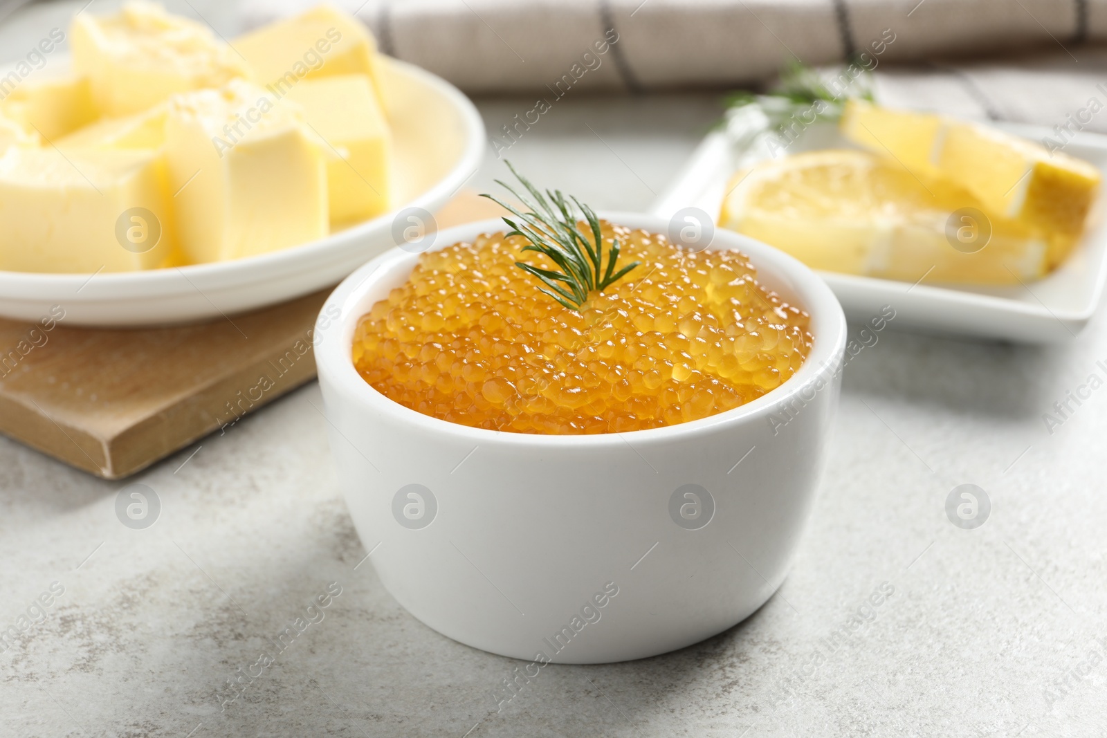 Photo of Fresh pike caviar and dill in bowl on light grey table, closeup