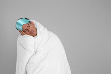 Photo of Man wrapped in blanket sleeping on grey background. Space for text