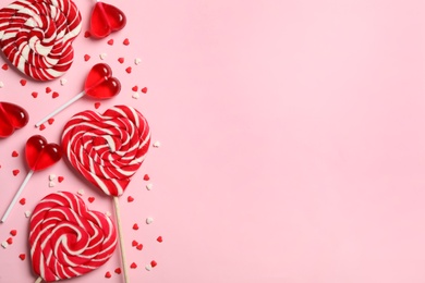 Photo of Sweet heart shaped lollipops and sprinkles on pink background, flat lay with space for text. Valentine's day celebration
