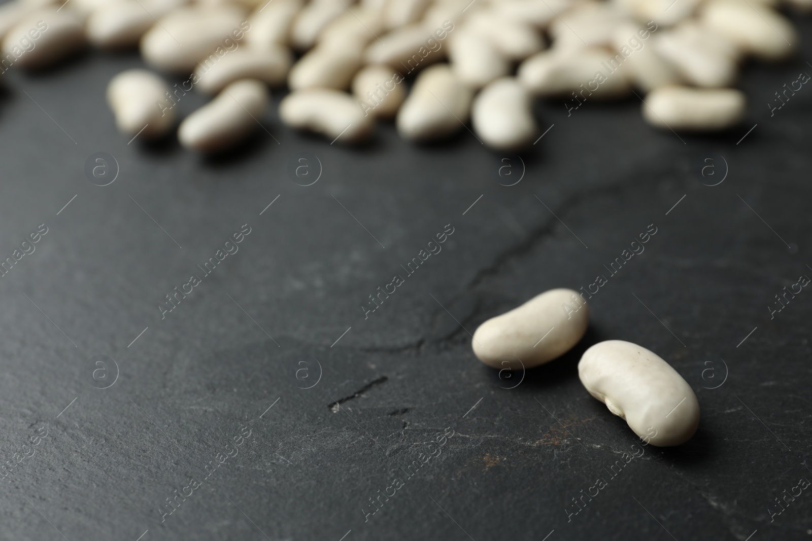 Photo of Raw beans on black background, closeup. Vegetable seeds