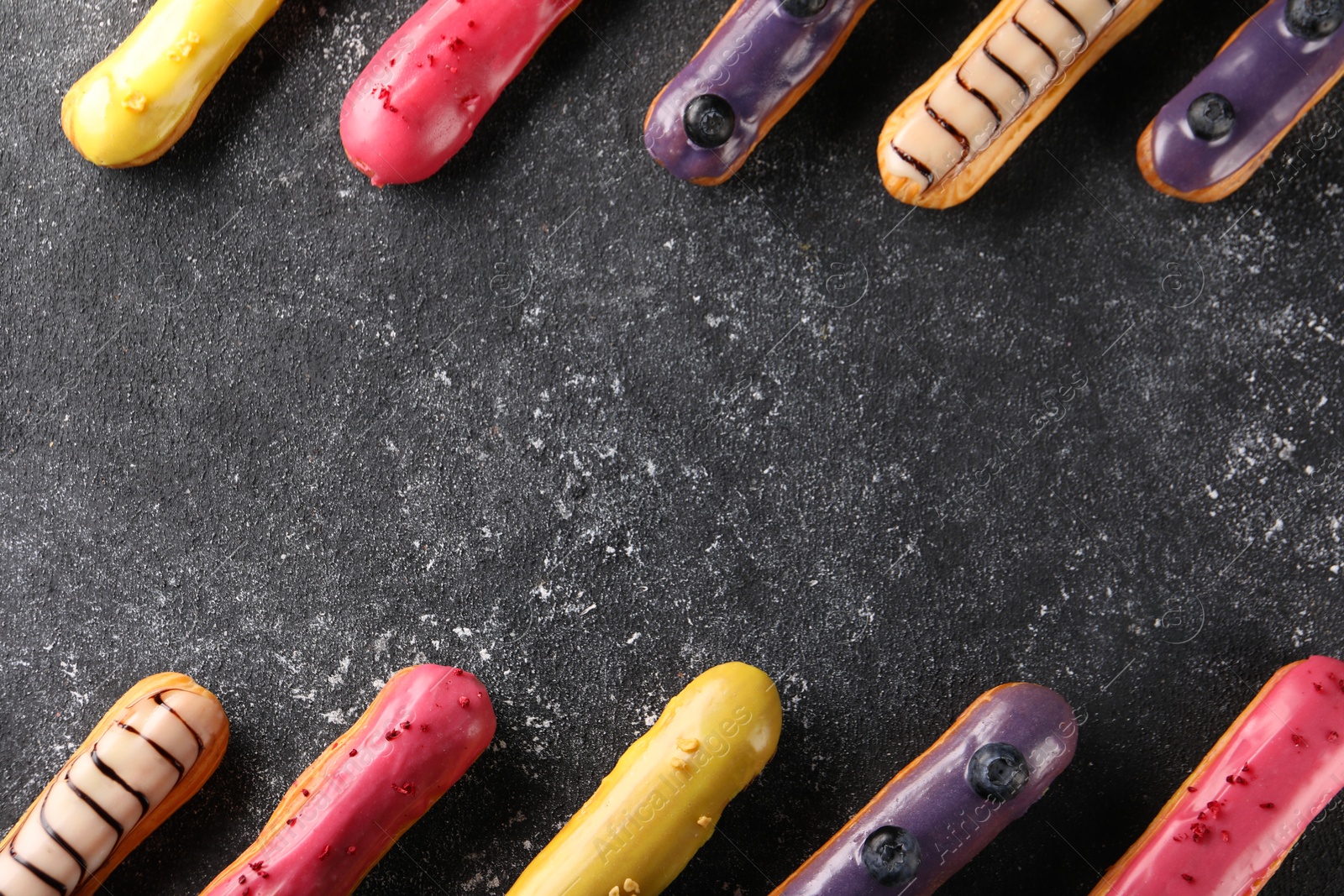 Photo of Different tasty glazed eclairs on dark textured table, flat lay. Space for text