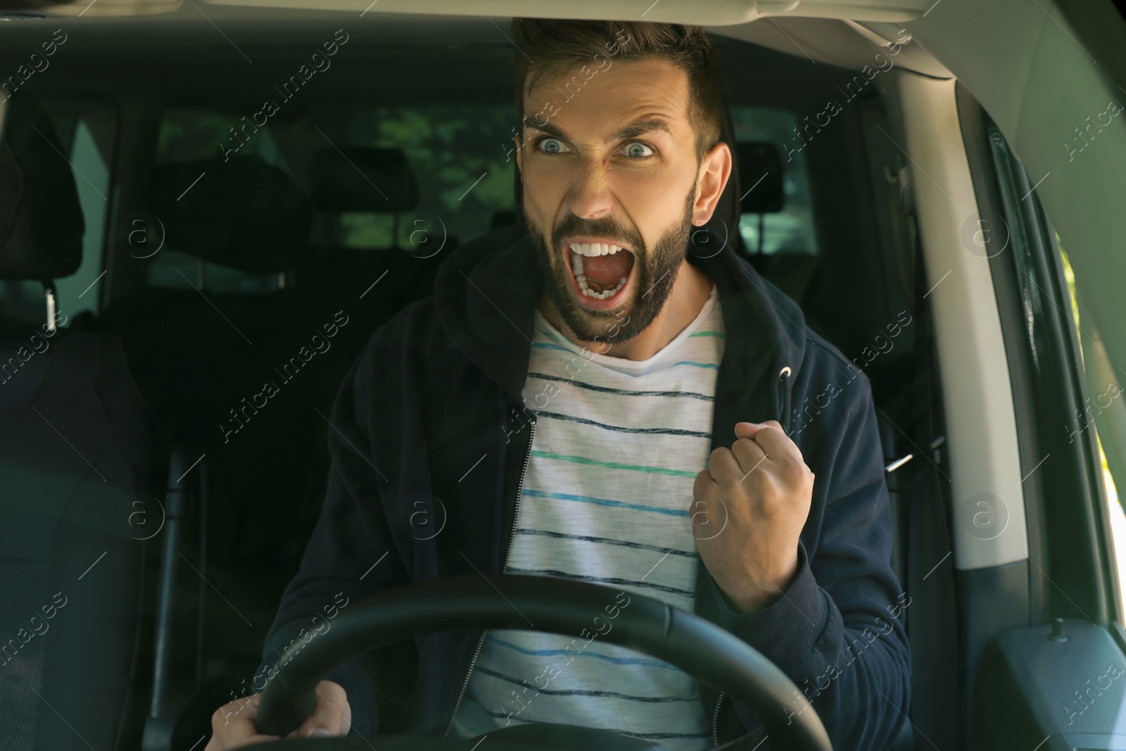 Photo of Stressed angry man in driver's seat of modern car, view through windshield