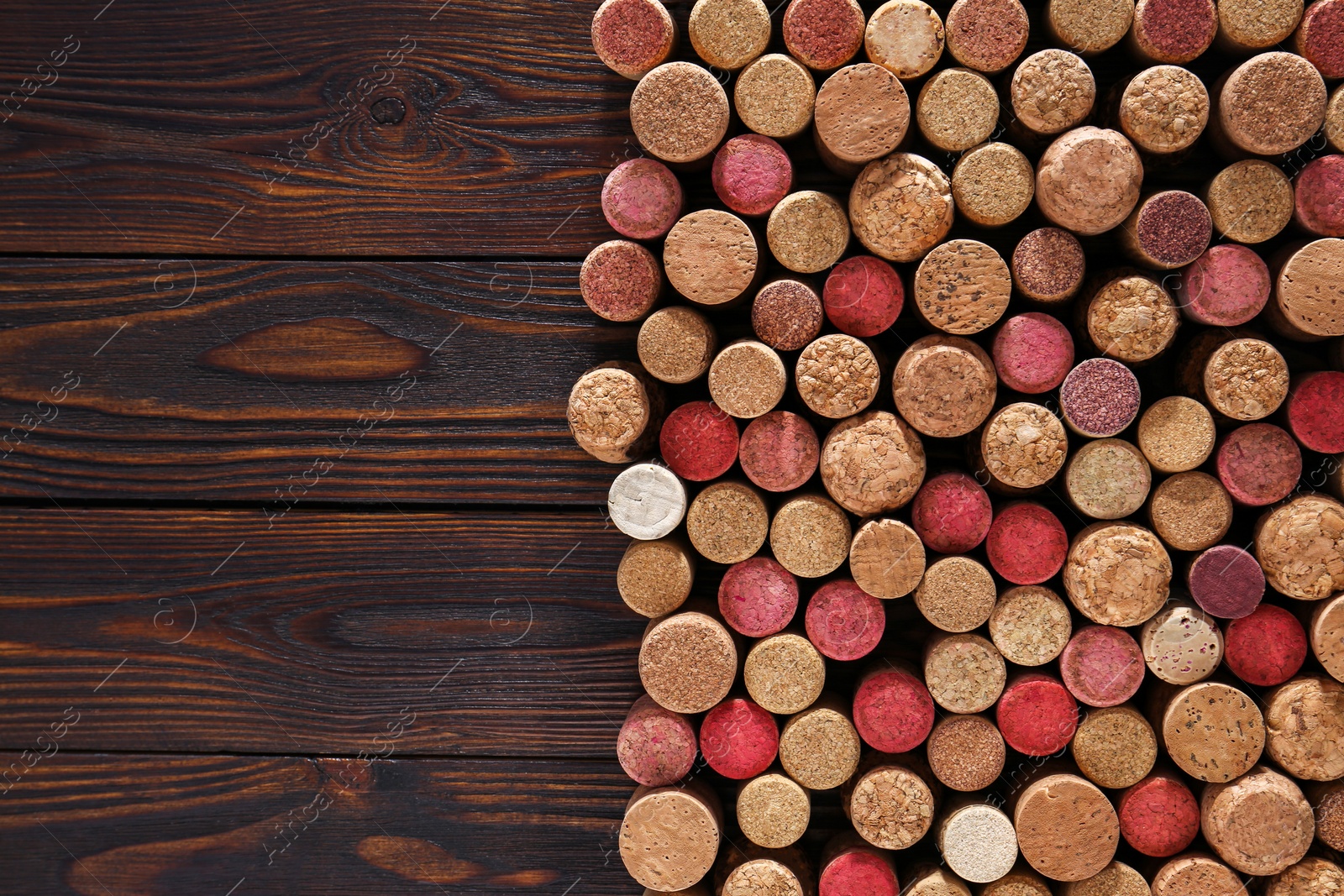 Photo of Many corks of wine bottles on wooden table, top view. Space for text