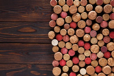 Photo of Many corks of wine bottles on wooden table, top view. Space for text