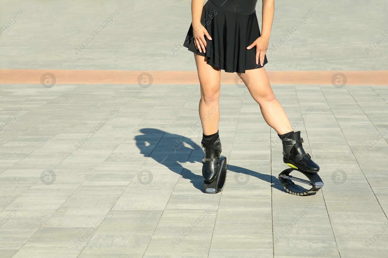 Photo of Woman in kangoo jumping boots outdoors on sunny day, closeup. Space for text