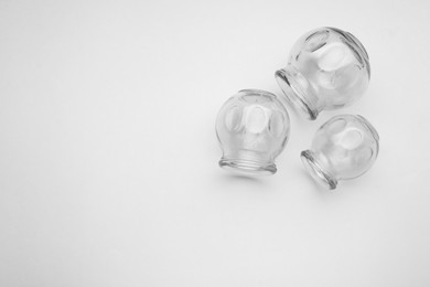 Photo of Glass cups on light grey background, flat lay and space for text. Cupping therapy