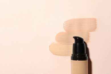 Liquid foundation and swatches on beige background, top view. Space for text