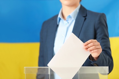 Photo of Woman putting vote into ballot box against Ukrainian flag, closeup. Space for text
