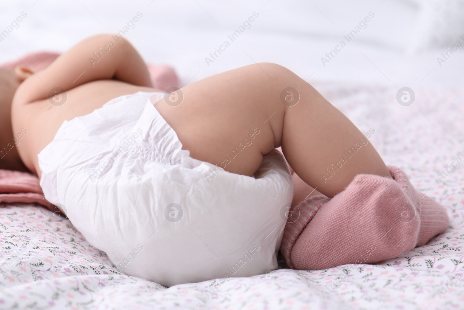 Photo of Little baby in diaper on bed, closeup