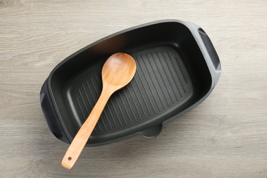 Photo of Black pot and spoon on wooden table, top view