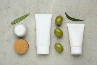 Photo of Cosmetic products with olive essential oil on light grey table, flat lay