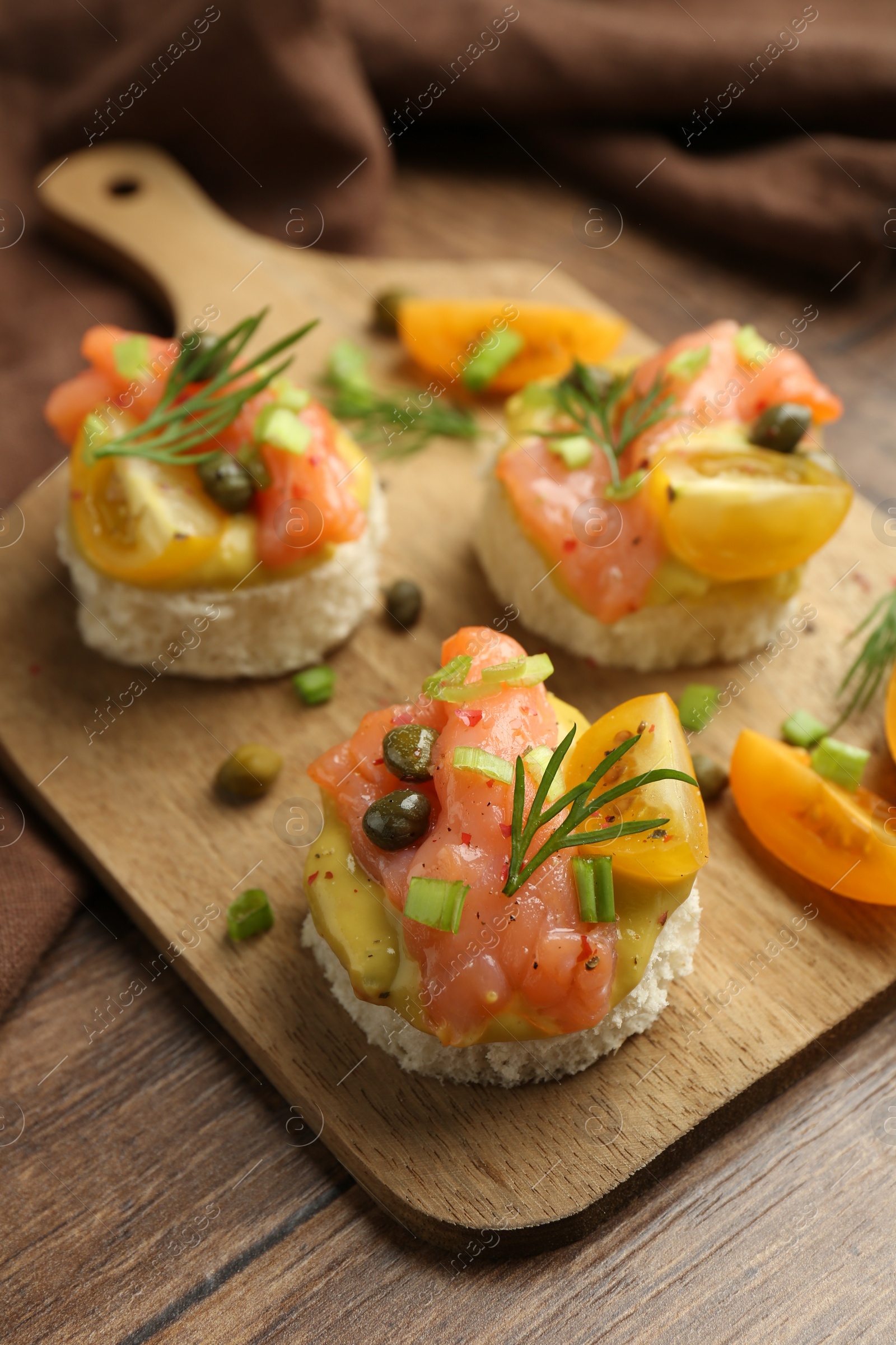 Photo of Tasty canapes with salmon served on wooden table, closeup