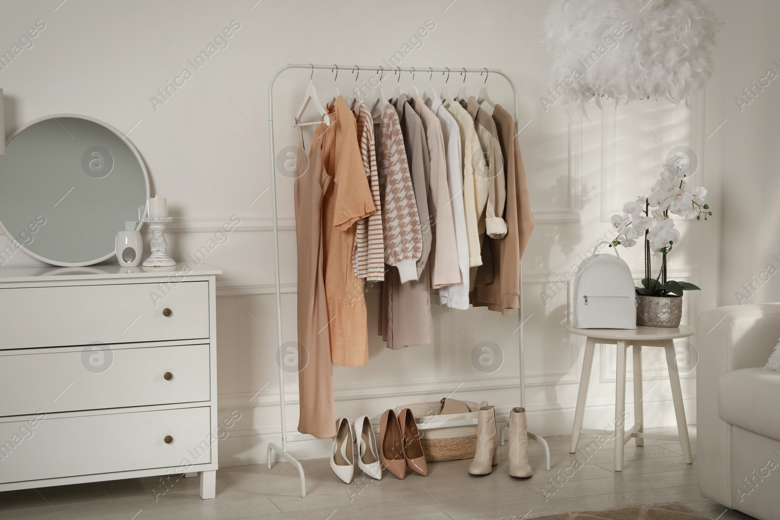 Photo of Modern dressing room interior with stylish clothes, shoes and beautiful orchid flowers