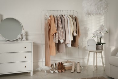 Modern dressing room interior with stylish clothes, shoes and beautiful orchid flowers