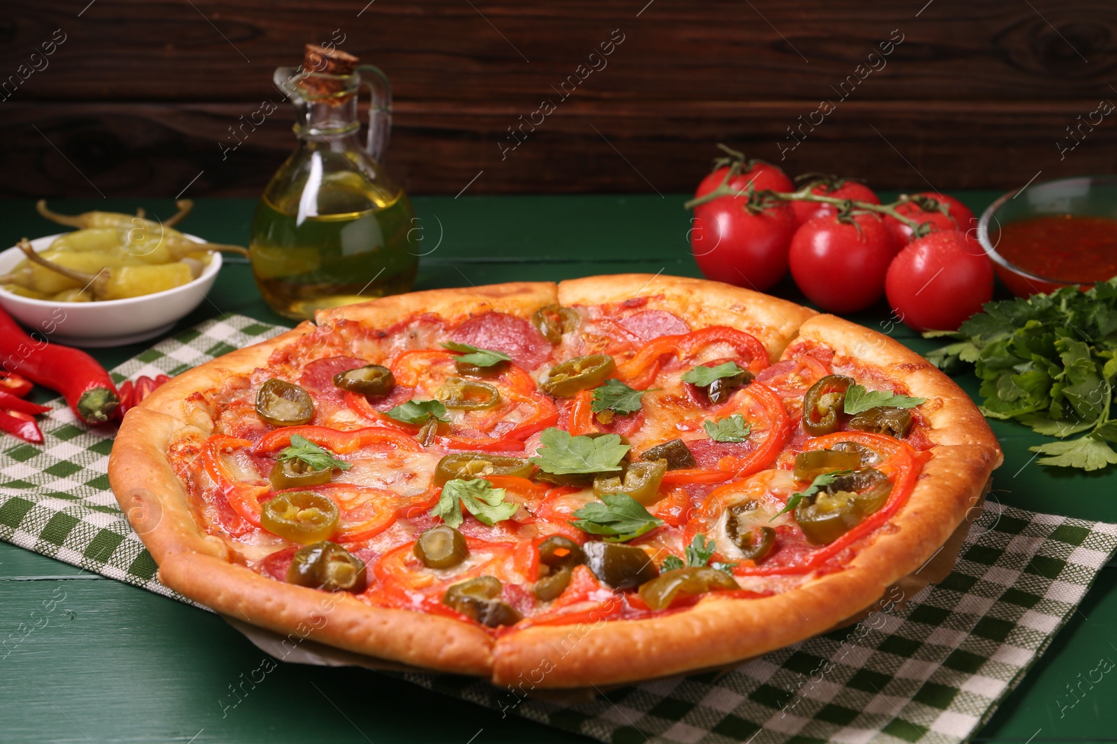 Photo of Delicious pizza Diablo and ingredients on green wooden table