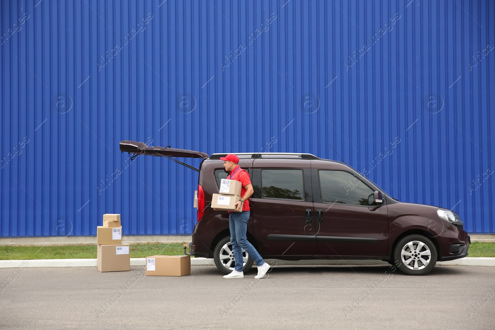 Photo of Courier loading packages in car outdoors, space for text