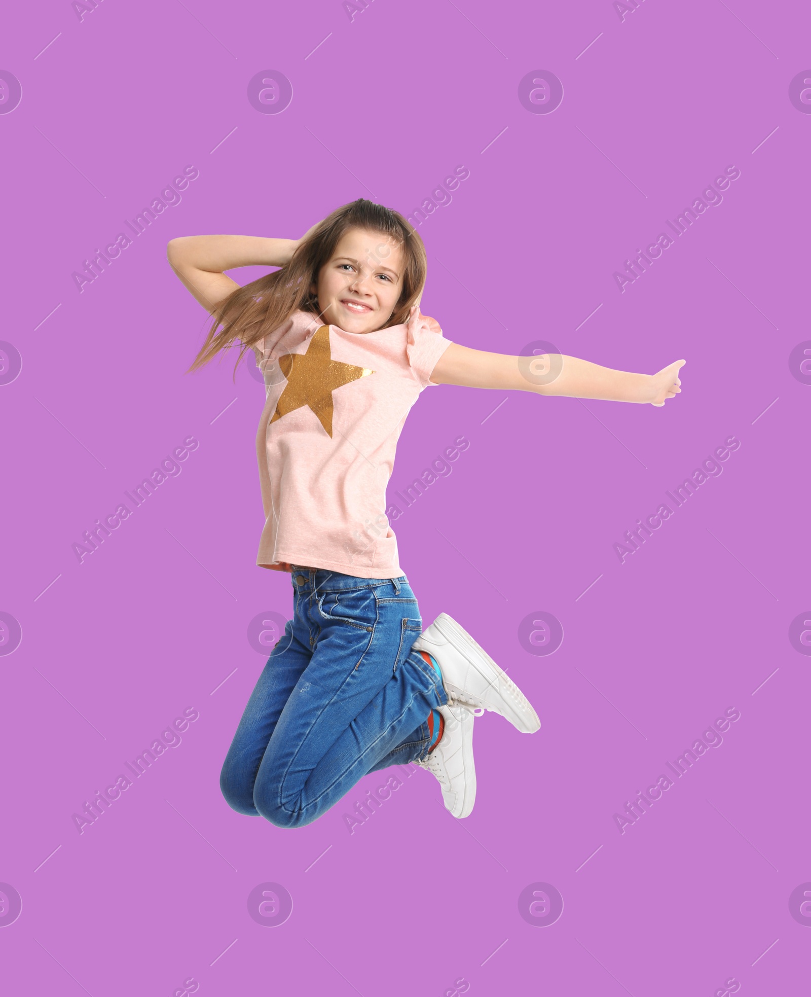 Image of Happy cute girl jumping on violet background