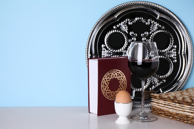 Photo of Symbolic Pesach (Passover Seder) items on table against light blue background, space for text
