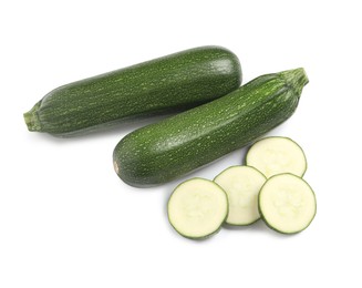 Whole and cut ripe zucchinis on white background, top view