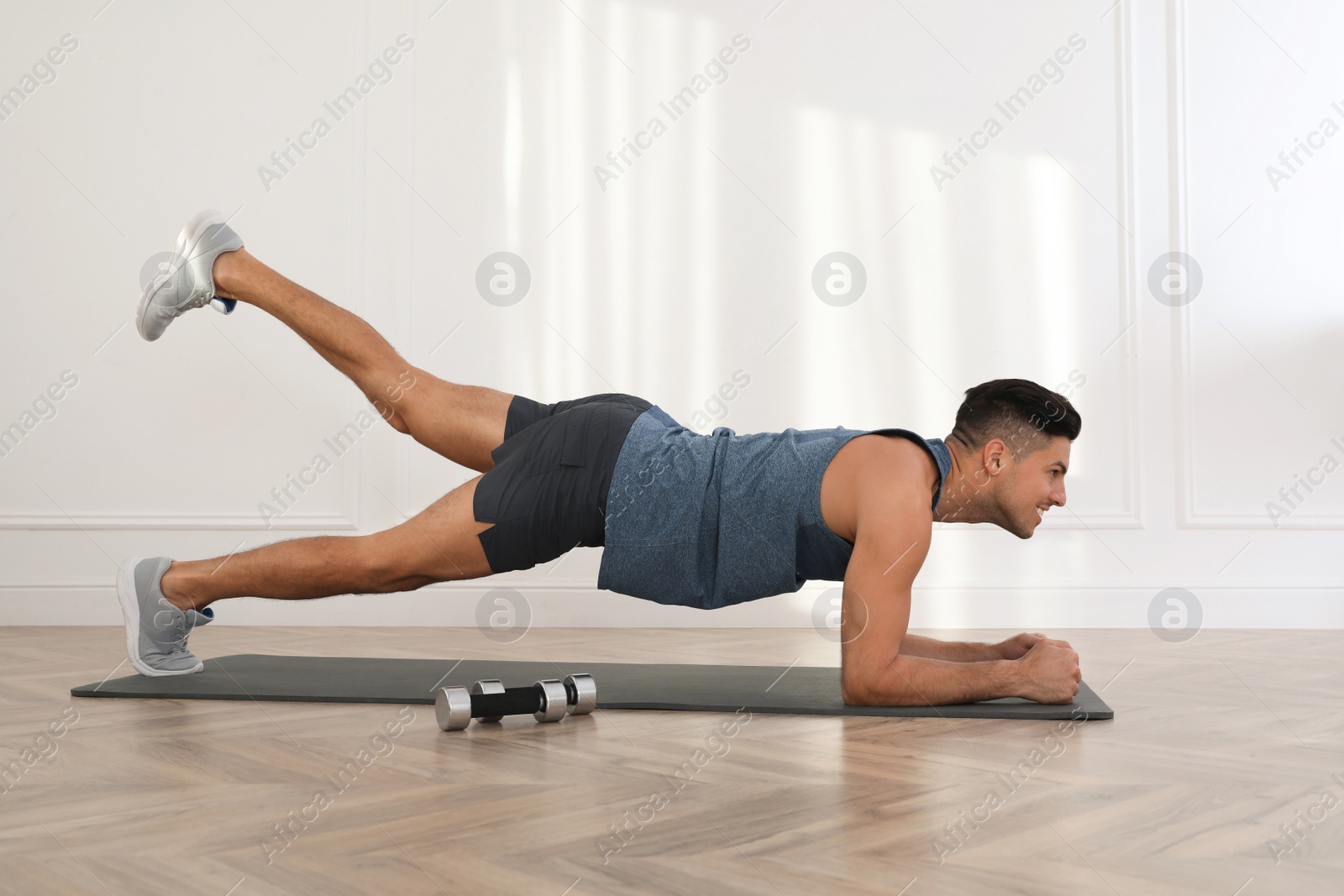 Photo of Handsome man doing exercise on yoga mat indoors