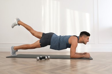 Handsome man doing exercise on yoga mat indoors