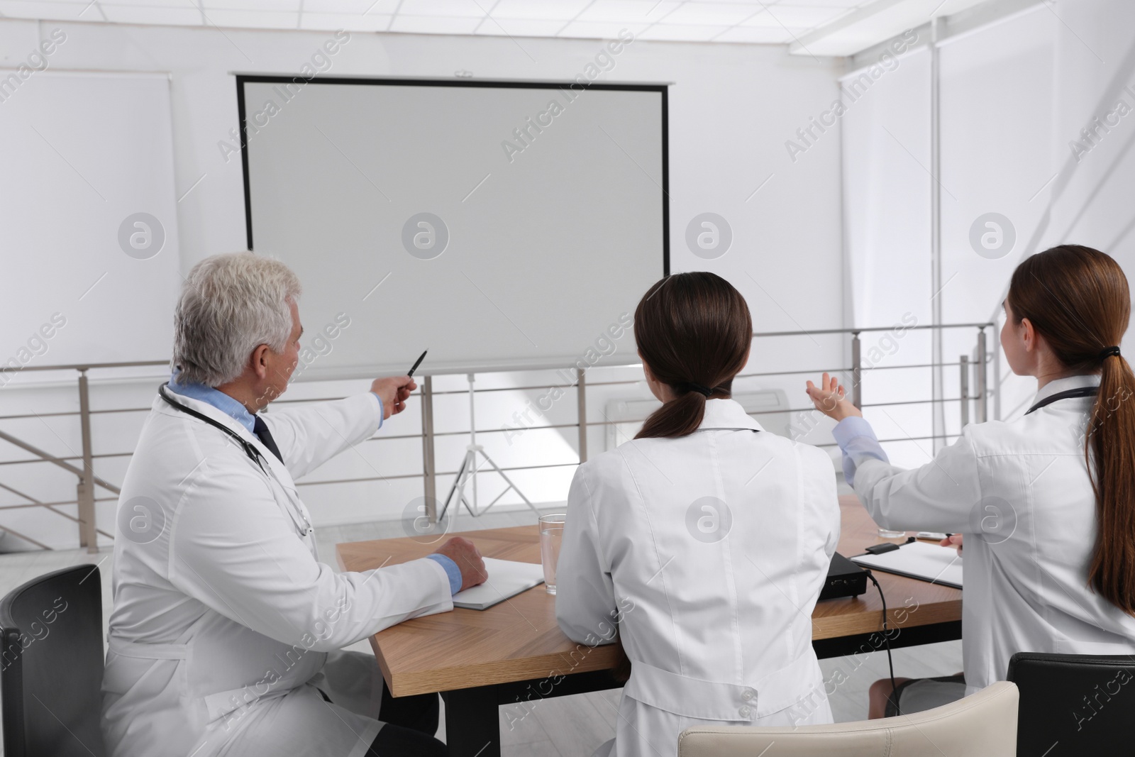 Photo of Team of doctors using video projector during conference indoors