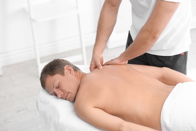 Relaxed man receiving back massage in wellness center