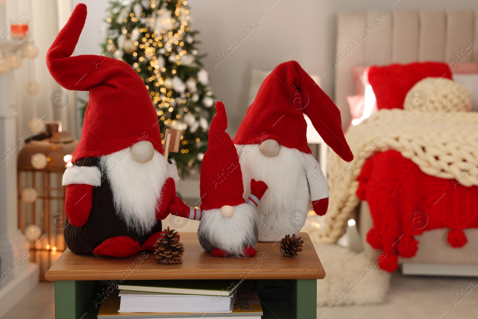 Photo of Cute Christmas gnomes on wooden table in room with festive decorations