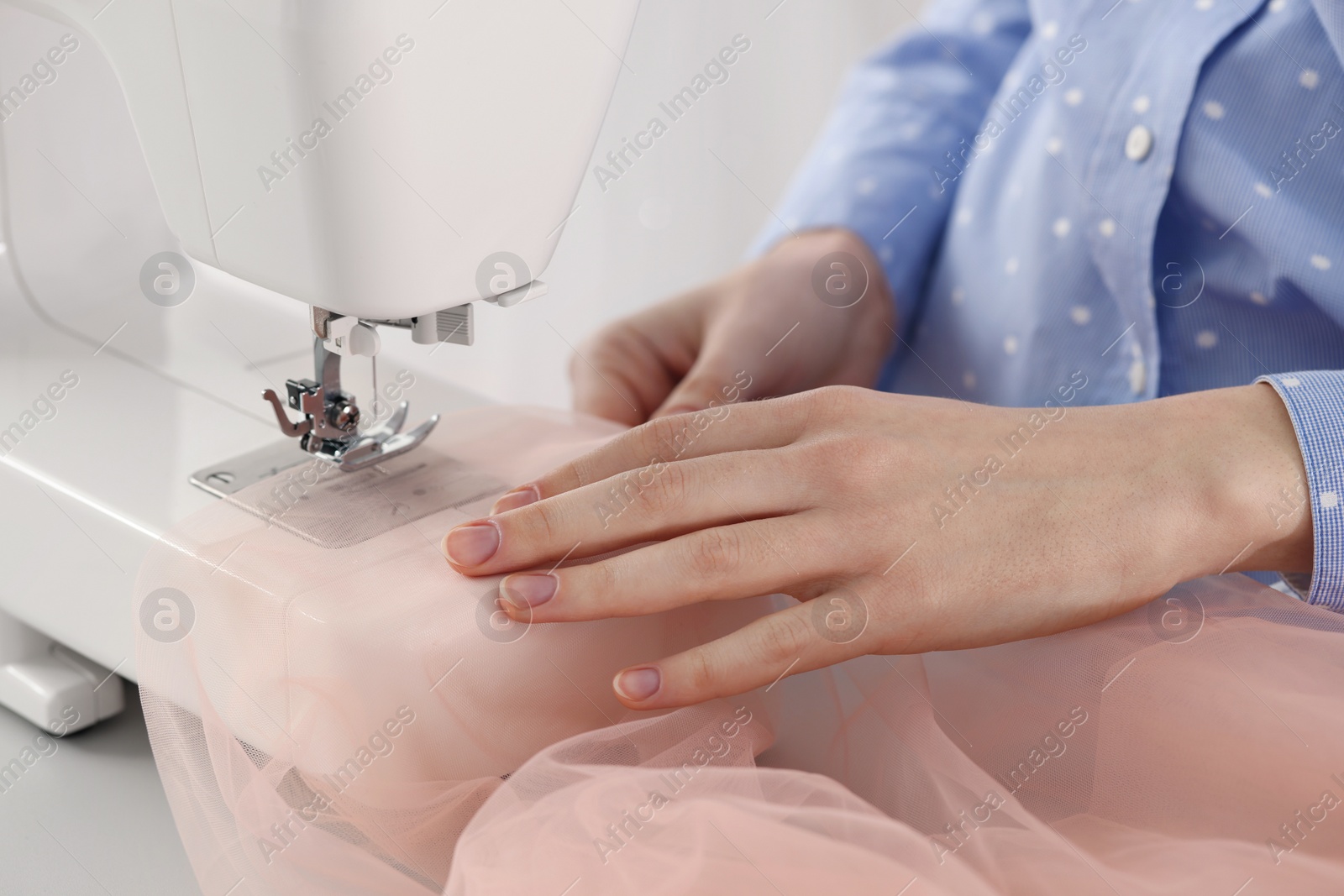 Photo of Dressmaker sewing new dress with machine in atelier, closeup