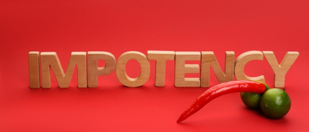 Photo of Word IMPOTENCY made of wooden letters and products symbolizing male sexual organ on red background