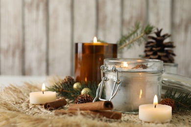 Photo of Burning scented conifer candles and Christmas decor on table. Space for text