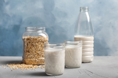 Photo of Jars with oat milk and flakes on table