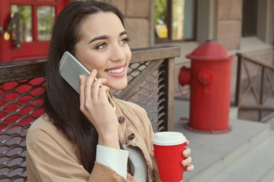 Photo of Young woman talking on mobile phone outdoors