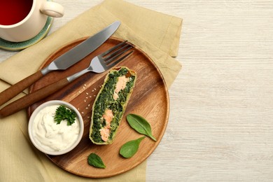 Photo of Delicious strudel with salmon and spinach served on light wooden table, flat lay. Space for text