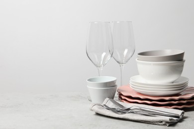 Beautiful ceramic dishware, glasses and cutlery on light grey table, space for text