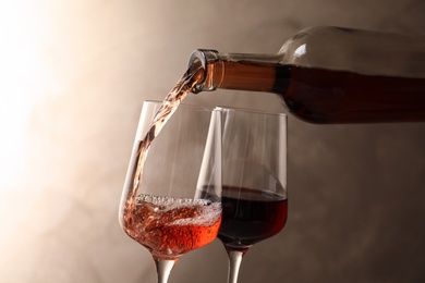 Photo of Pouring wine from bottle into glass on color background