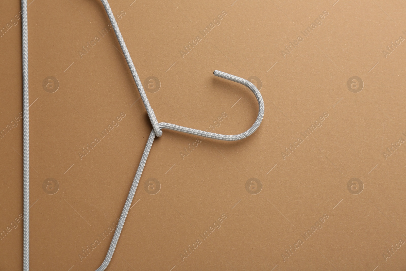 Photo of Empty hanger on brown background, top view. Space for text