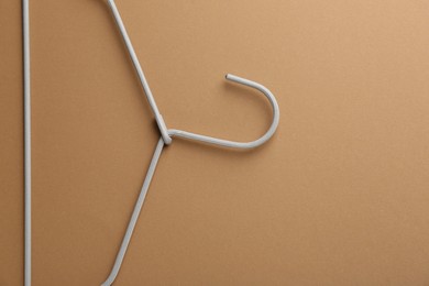 Empty hanger on brown background, top view. Space for text