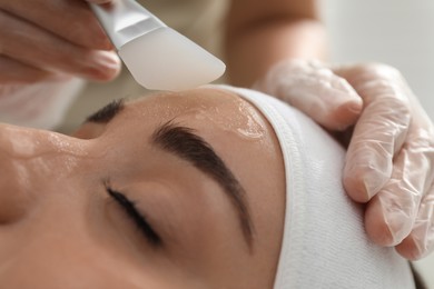 Young woman during face peeling procedure in salon, closeup